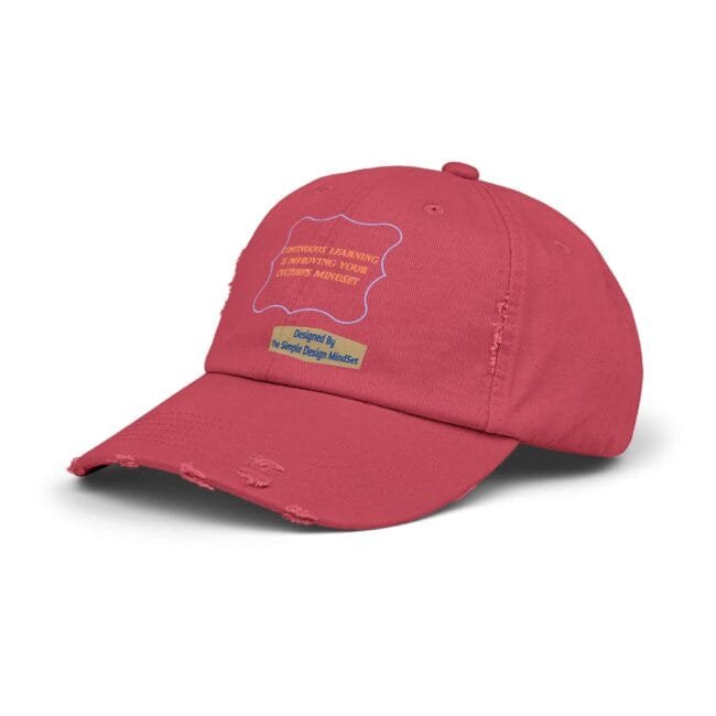 Close-up of a red baseball cap showing a yellow sticker label and a light-blue outline patch on the front, with frayed brim edges.