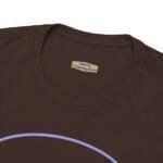 Close-up of a brown t-shirt neckline showing a beige label with blue text: 'Designed By The Simple Design MindSet' near the collar, with part of a lavender arc design visible at the bottom edge.