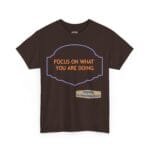 Brown T-shirt featuring a purple decorative badge outline with orange text: 'FOCUS ON WHAT YOU ARE DOING'.