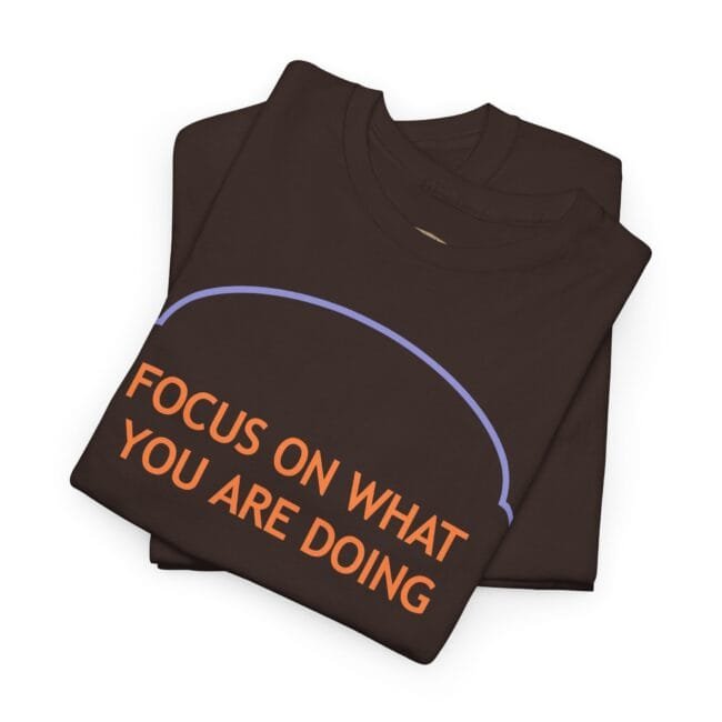 Brown sweatshirt folded with bold orange lettering: 'FOCUS ON WHAT YOU ARE DOING' under a purple curved arc.