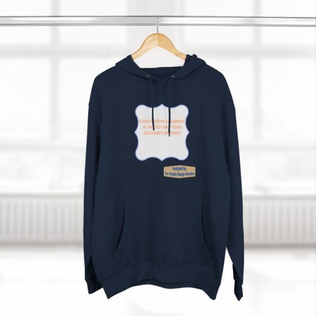 Navy hoodie on a hanger featuring a pale blue wavy frame with orange text about continuous learning, plus a small designer label.