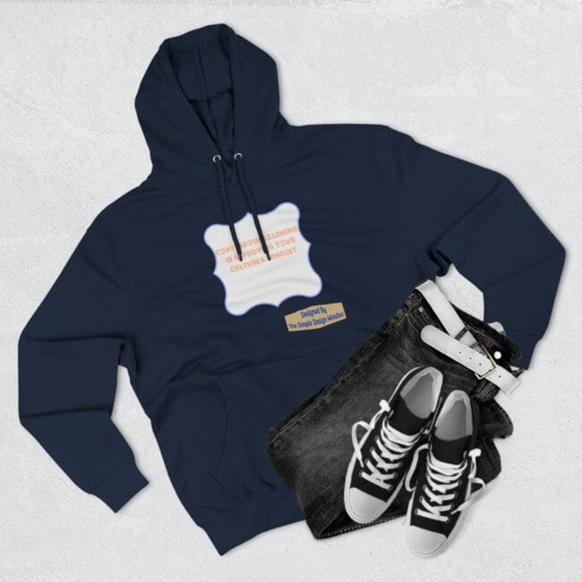 Navy hoodie with a pale purple decorative label graphic on the chest, paired with dark jeans and white‑trimmed black sneakers for a casual outfit.