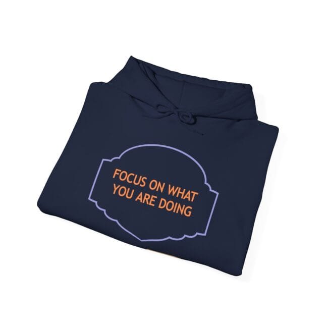 Navy hoodie folded with a decorative purple frame and orange text reading 'FOCUS ON WHAT YOU ARE DOING'