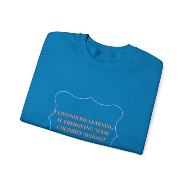 Blue folded T-shirt with an orange quote inside a decorative purple frame: 'Continuous learning is improving your cultures' mindset'