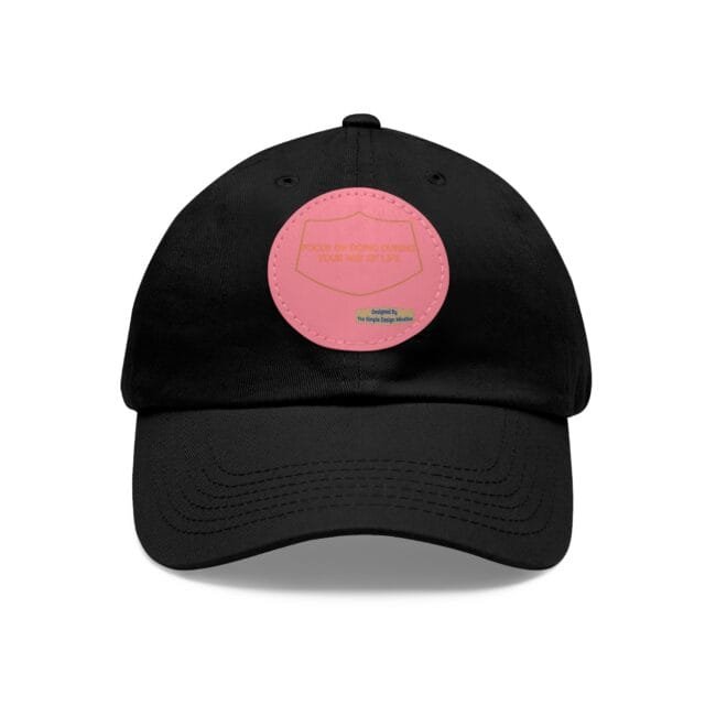 Black baseball cap with a pink circular patch on the front, featuring a shield outline design.