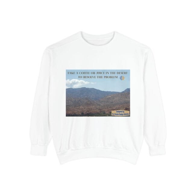 White sweatshirt featuring a desert landscape graphic with a blue sky and mountains, overlaid by the phrase 'Take a coffee or juice in the desert to resolve the problem' and a small bottom-right designer label.