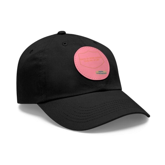 Black baseball cap with a pink circular patch on the front, featuring a shield shape and small text.