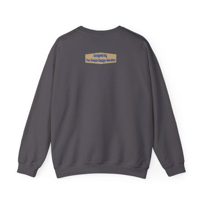 Back view of a dark gray crewneck sweatshirt with a small tan label on the upper back reading 'Designed By The Simple Design MindSet'