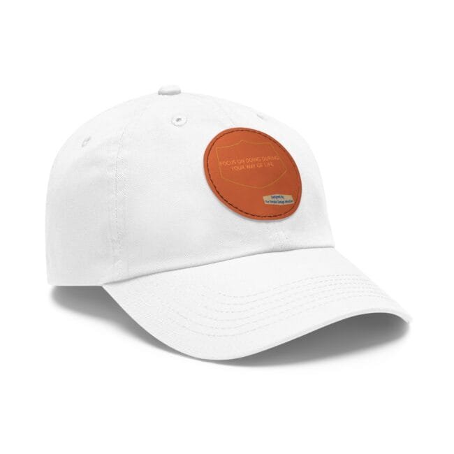 White baseball cap with an orange shield-shaped patch on the front displaying a motto text.