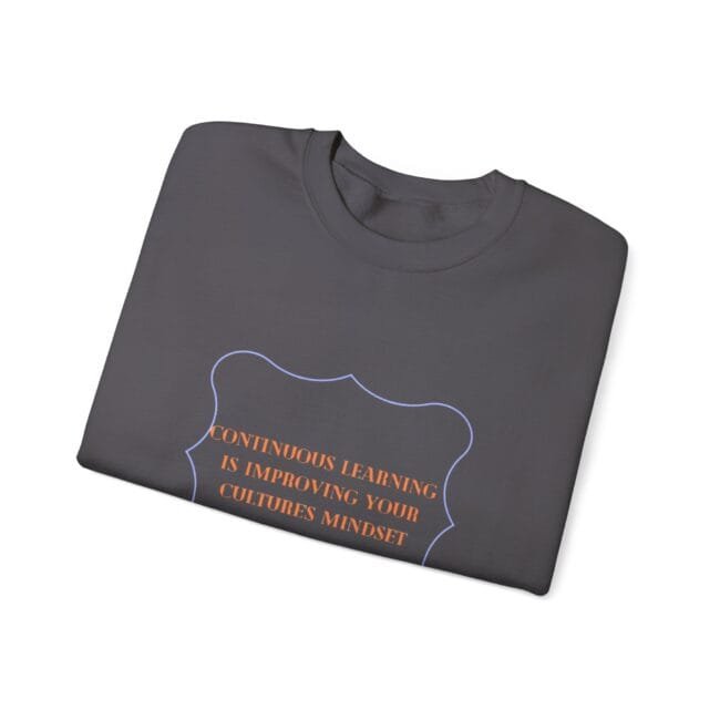 folded dark gray t-shirt with a blue decorative frame and orange quote: 'Continuous learning is improving your culture's mindset'
