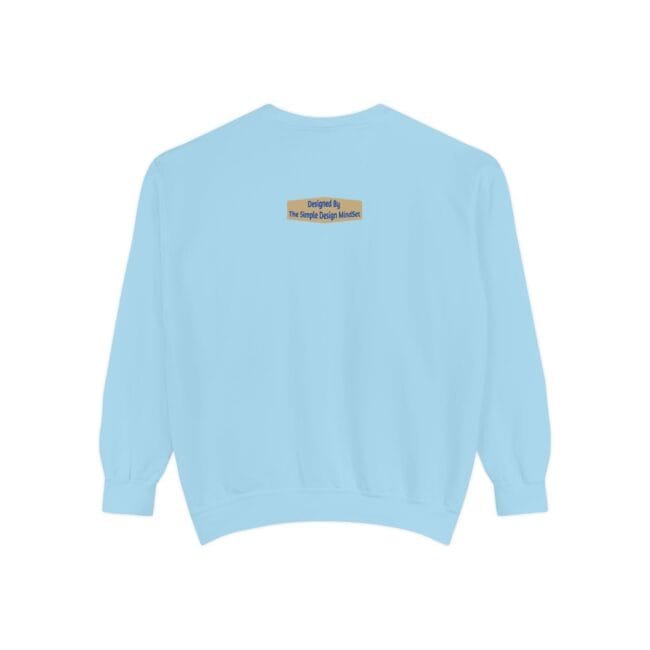 Back view of a light blue sweatshirt with a small beige label centered near the neck reading: 'Designed By The Simple Design Mindset'
