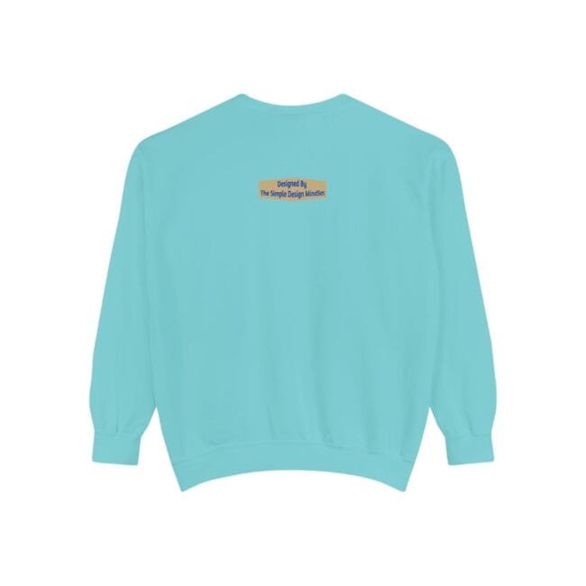 Back view of a turquoise sweatshirt with a small yellow label on the upper back reading 'Designed By The Simple Design Mindset'.)