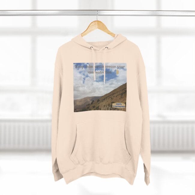 Beige hoodie with a square landscape print on the chest showing mountains and sky, plus the phrase 'Keep calm and increase your concentration'.