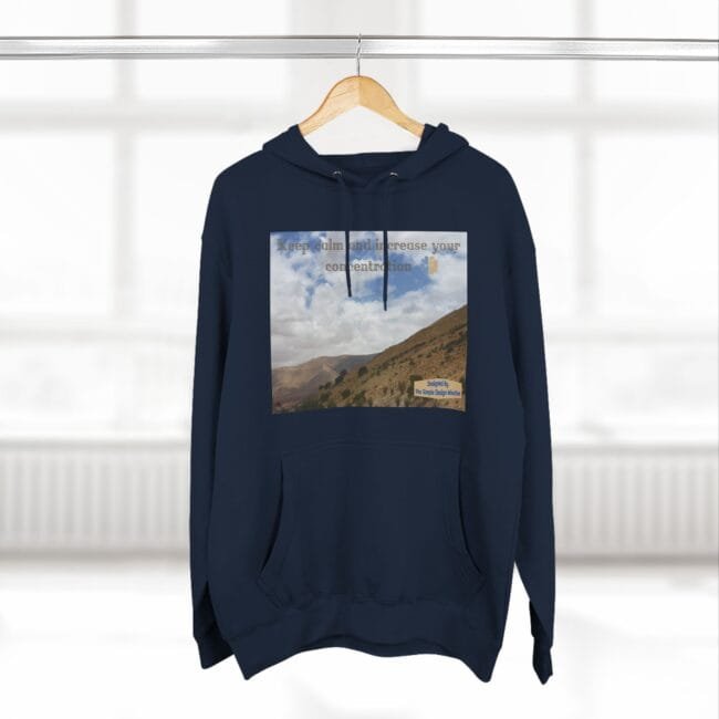 Navy hoodie with a rectangular landscape print of hills and cloudy sky on the chest and the text “Keep calm and increase your concentration.”