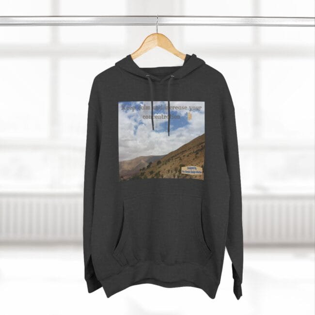Dark charcoal hoodie on a hanger featuring a rectangular landscape print (hills and blue sky) with the text 'Keep calm and increase your concentration'.
