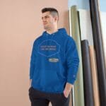Man modeling a blue hoodie with an orange slogan reading 'FOCUS ON WHAT YOU ARE DOING' in a studio with rolled fabrics in the background.