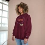 Person wearing a burgundy hoodie with the slogan “FOCUS ON WHAT YOU ARE DOING” inside a decorative blue shape, standing in a bright room by a window.