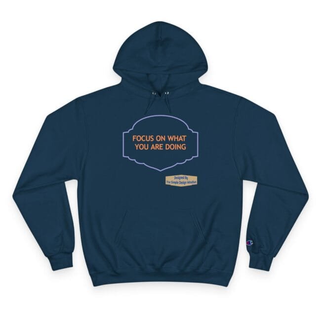 Navy hoodie with a purple framed label reading 'FOCUS ON WHAT YOU ARE DOING' in orange text and a small beige designer tag below.