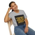 Woman sits on a wooden chair, smiling, wearing a gray tee with a neon-text graphic: “A PRINCESS IS A GIRL OR A WOMAN WHO CONSERVES HER ETHICS.”