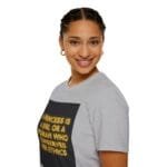 Smiling woman wearing a light gray T-shirt with a neon-yellow quote inside a black rectangle on the front.