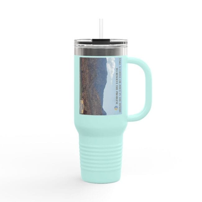 Mint green insulated tumbler with a clear lid and straw, displaying a desert canyon label on its side.