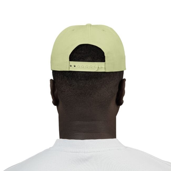 Back view of a person wearing a pale yellow baseball cap with an adjustable strap, short hair visible at the nape, and a white shirt.