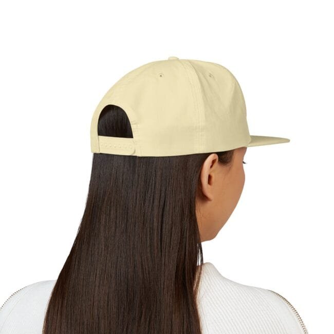 Back view of a pale yellow baseball cap on a person with long dark hair, showing the adjustable strap at the back and a curved brim