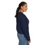 A woman in a navy sweatshirt seen from the side, smiling, with braided hair and jeans.