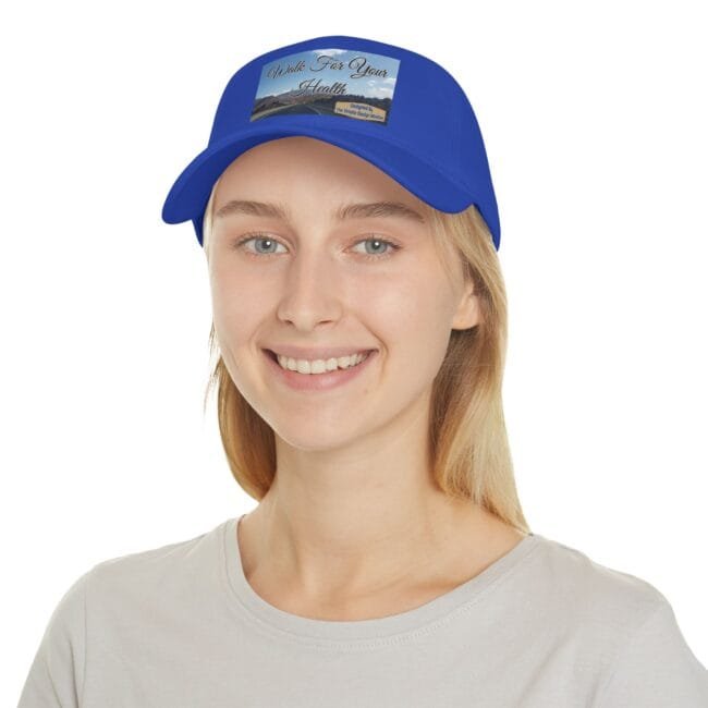 Young woman wearing a royal blue cap with a 'Walk For Your Health' patch on the front, smiling at the camera.