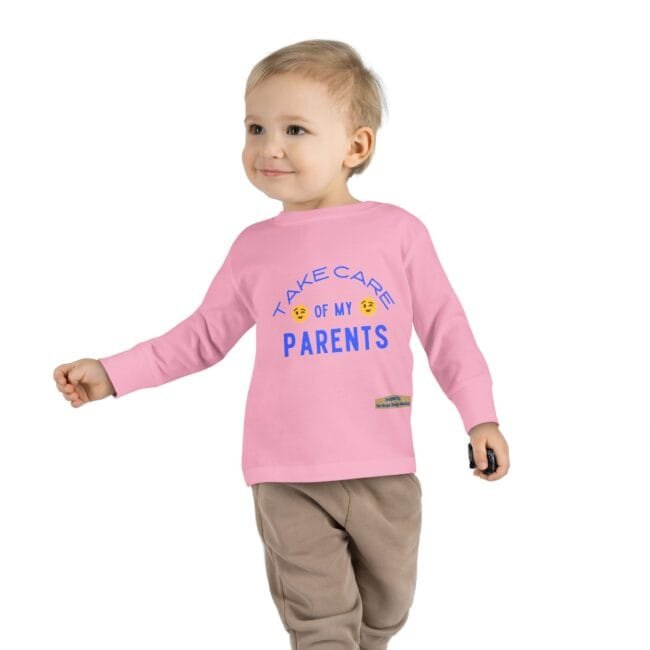 Cute toddler in a pink long-sleeve shirt that reads 'Take care of my PARENTS' in blue, smiling and walking with a small object in hand.