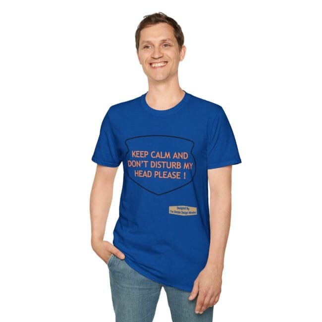 Smiling man wearing a blue t-shirt with orange text: 'KEEP CALM AND DON'T DISTURB MY HEAD PLEASE!'; shield graphic on front, small designer label at bottom right.