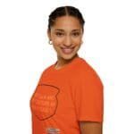 Smiling woman with braided hair in an orange T-shirt, shown in a right-side profile.
