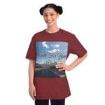 Smiling young woman wearing a maroon oversized T-shirt with a front graphic that says 'Walk For Your Health' over a road and sky scene.