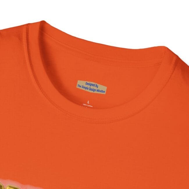 Close-up of an orange t-shirt neckline showing a small blue designer tag reading 'Designed By The Simple Design MindSet' near the collar edge.