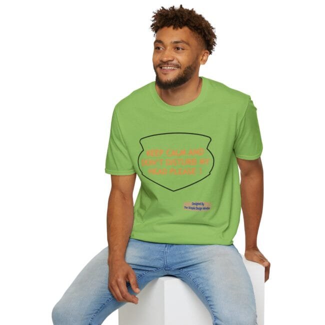 Man in a bright green t-shirt sitting on a white block, shirt reads 'KEEP CALM AND DON'T DISTURB MY HEAD PLEASE!'