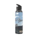 Reusable water bottle with a blue sky label reading 'For Your Health' and a highway scene in the background, black spout lid nearby.