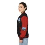 Side view of a woman wearing a black and red varsity jacket with patches on the chest and sleeve.