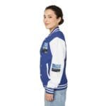 Side view of a woman wearing a blue and white varsity jacket with patches on the sleeves and chest, smiling slightly