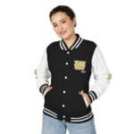Woman wearing a black and white varsity jacket with striped cuffs and collar, hands in pockets, smiling at the camera