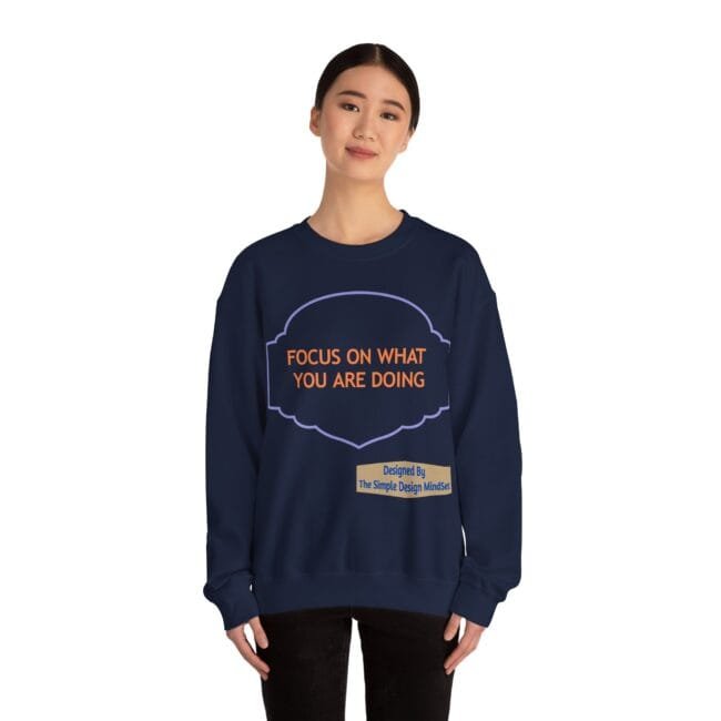 Navy sweatshirt on a woman with an orange message, 'FOCUS ON WHAT YOU ARE DOING,' inside a purple decorative frame.