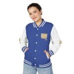 Woman wearing a blue and white varsity jacket with striped cuffs and collar, hands in pockets, smiling at the camera.