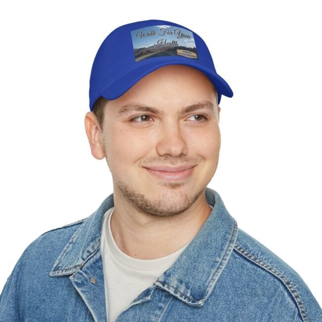 Smiling man in a denim jacket wearing a bright blue cap with a 'Walk For Your Health' patch, looking to the side.