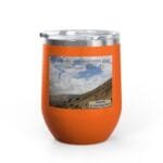 Orange insulated tumbler with a sticker that reads, 'Keep calm and increase your concentration' over a mountain landscape photo, topped with a clear lid.