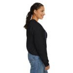 Side view of a smiling woman wearing a black sweatshirt and blue jeans.
