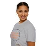 Smiling woman wearing a gray T-shirt with orange text reading 'KEEP CALM AND DON'T DISTURB MY HEAD PLEASE!' against a white background.