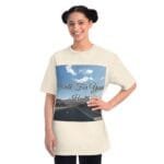 Beige T-shirt worn by a smiling woman featuring a road, blue sky, and the text 'Walk For Your Health'.