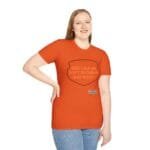 Smiling woman wearing an orange T-shirt with a shield-shaped graphic that reads, 'KEEP CALM AND DON'T DISTURB MY HEAD PLEASE!'