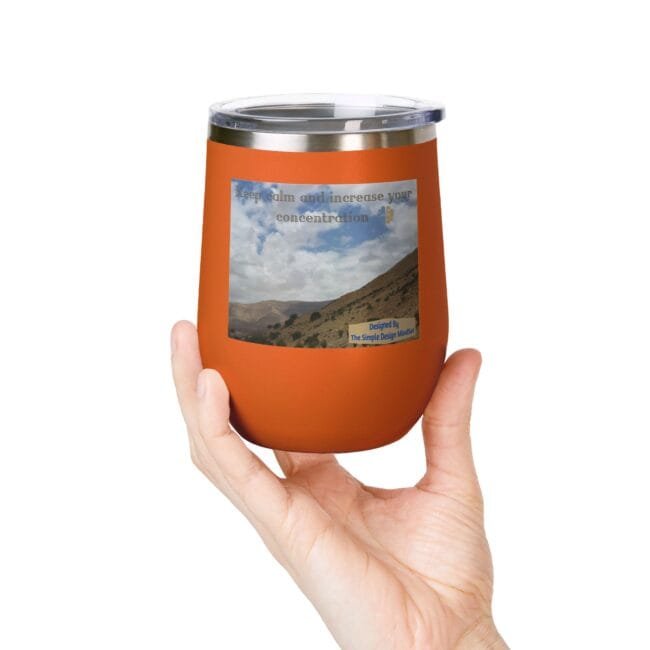 Orange insulated tumbler held in a hand; label features a mountain landscape and the text 'Keep calm and increase your concentration'.