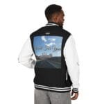Back view of a man wearing a black-and-white varsity jacket with a large graphic on the back showing a highway under a blue sky and the text 'Walk For Your Health' (promotional message).