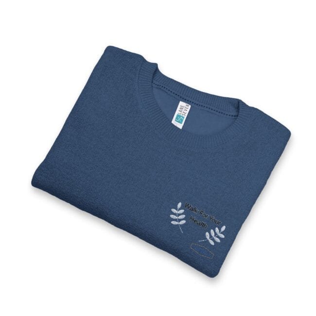 Folded blue knit sweater with white leaf embroidery and the text 'Walk For Your Health' on the front.
